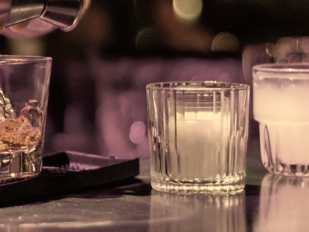 Glassware set out along a bar top under low light.