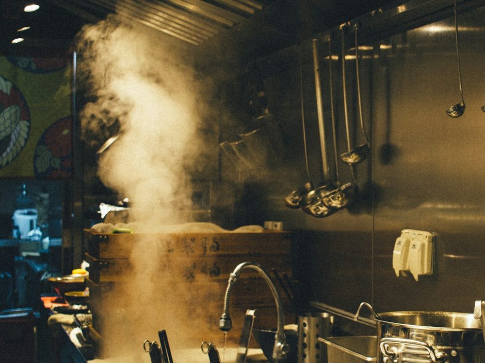 Steam rising from stacked bamboo steamers on a busy line.